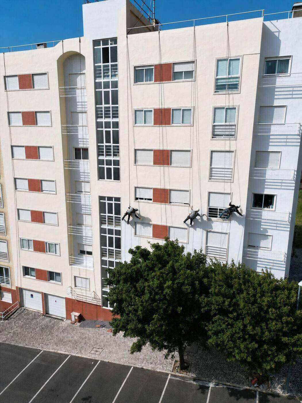 Técnicos em rappel a pintar a empena do prédio: pintura de fachada, Lisboa