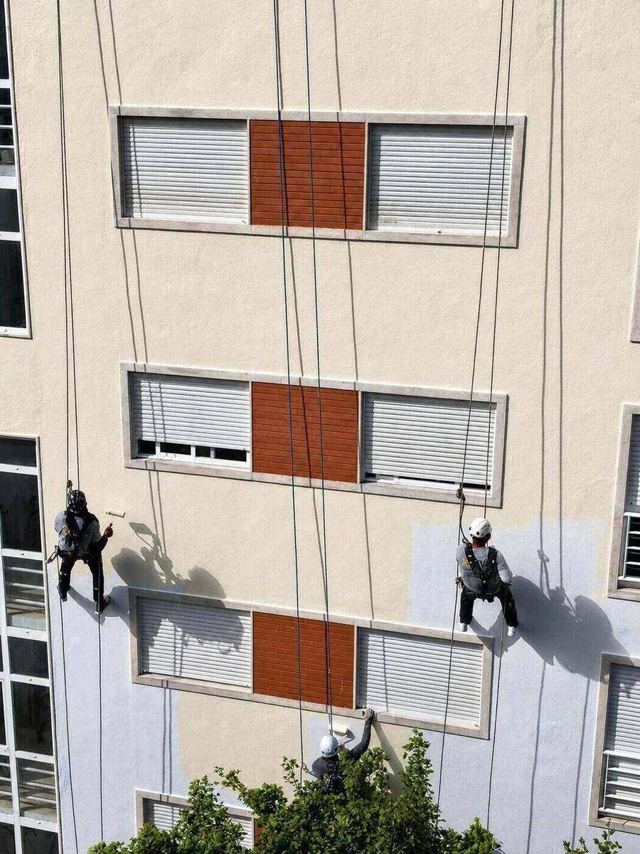 Pormenor de dois alpinistas industriais a pintar a fachada em rappel: Lisboa