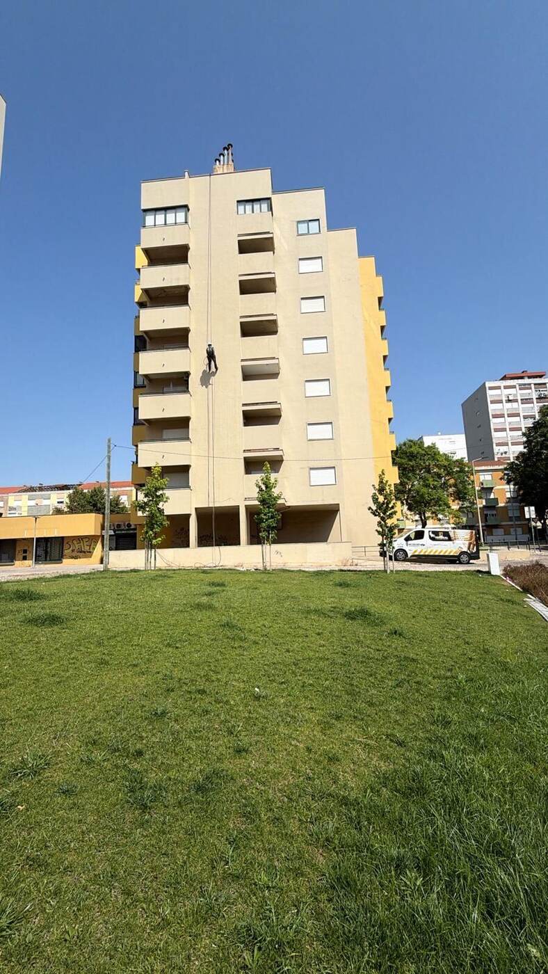 Prédio em pintura de fachada por corda em Lisboa, com a carrinha da RJ Vertical