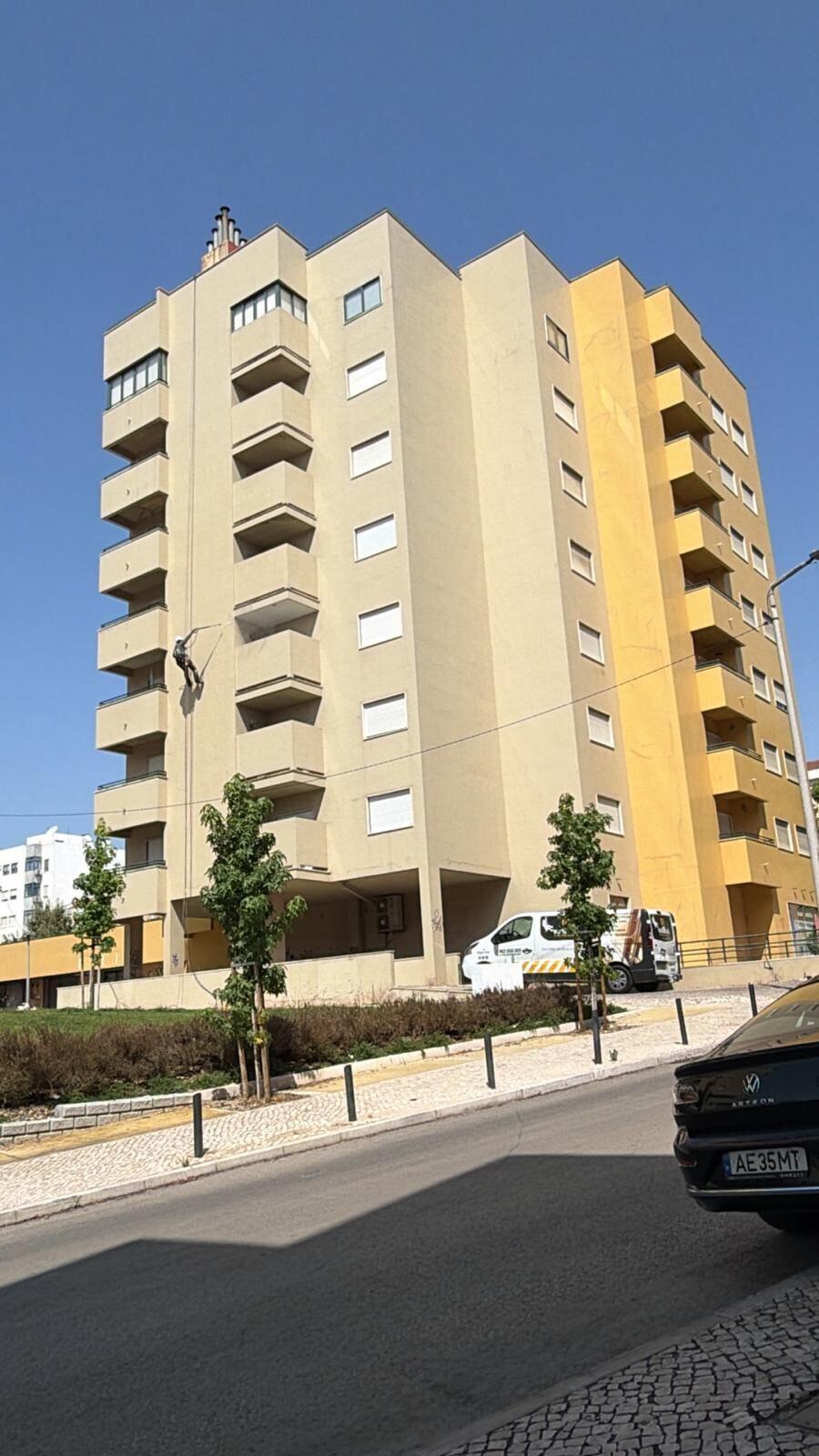 Pintura de fachada de prédio de vários andares por corda em Lisboa